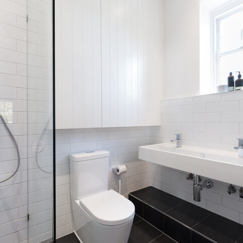 Small ensuite bathroom with white tiling laid in a brick pattern